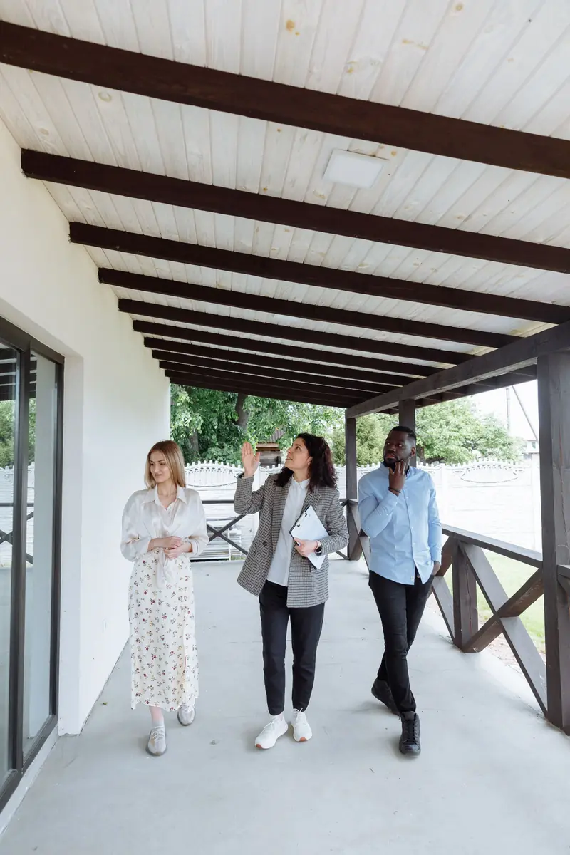 Agent walking clients along the porch of a renovated home